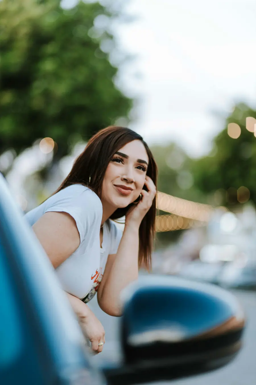 Mulher sorrindo encostada num carro