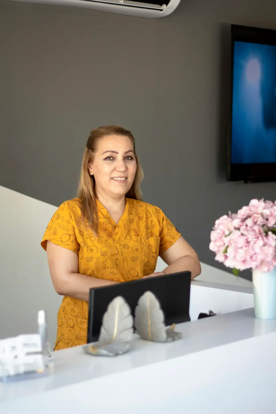 Recepcionista sorrindo atrás do balcão de uma clínica