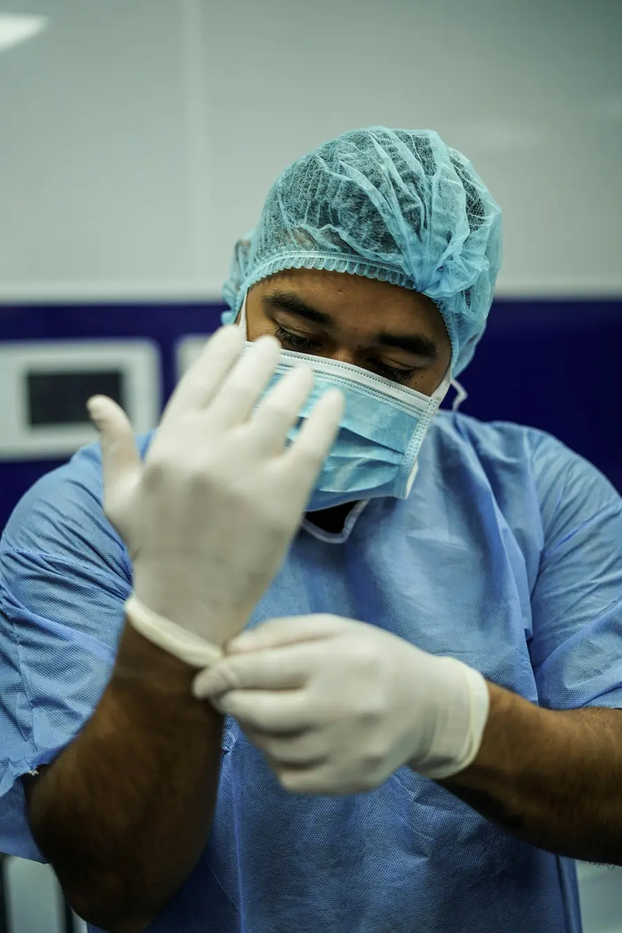 Médico sorridente de jaleco num ambiente hospitalar claro, tons de branco e azul