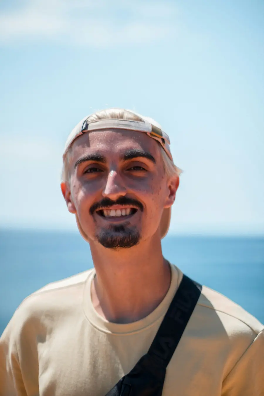 Homem sorrindo com o mar ao fundo