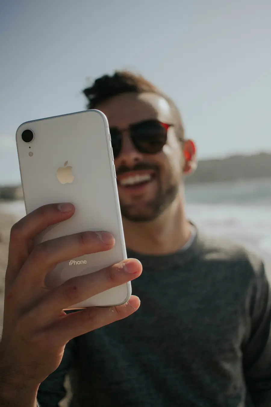 Homem de óculos escuros com o celular na mão