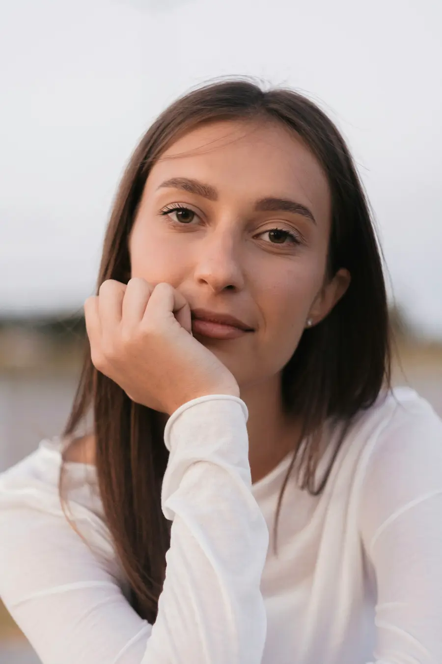 Jovem sorrindo com a mão no queixo
