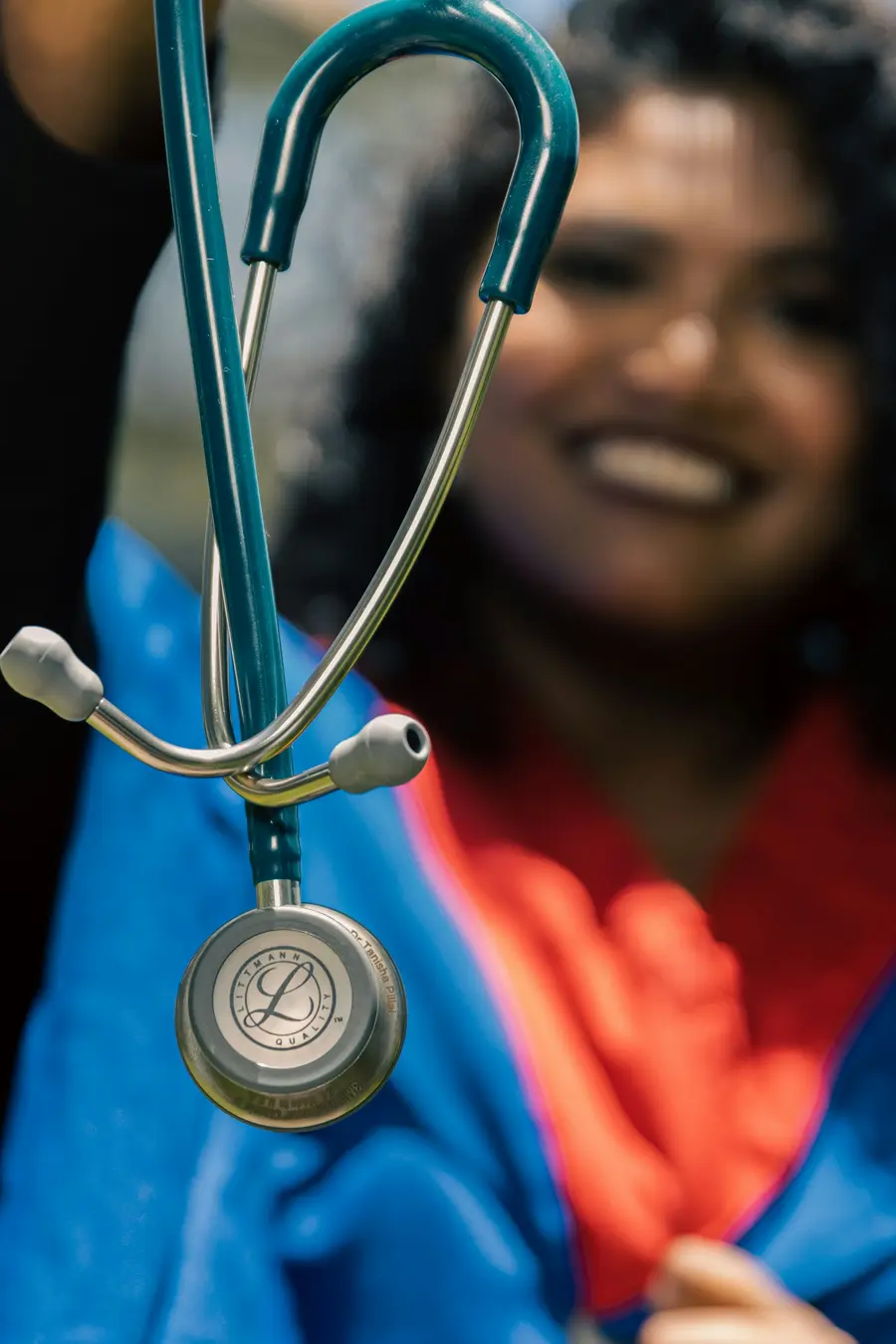 Paciente adulta sorridente sentada conversando com um médico que segura uma prancheta, em consultório claro e detalhes em azul