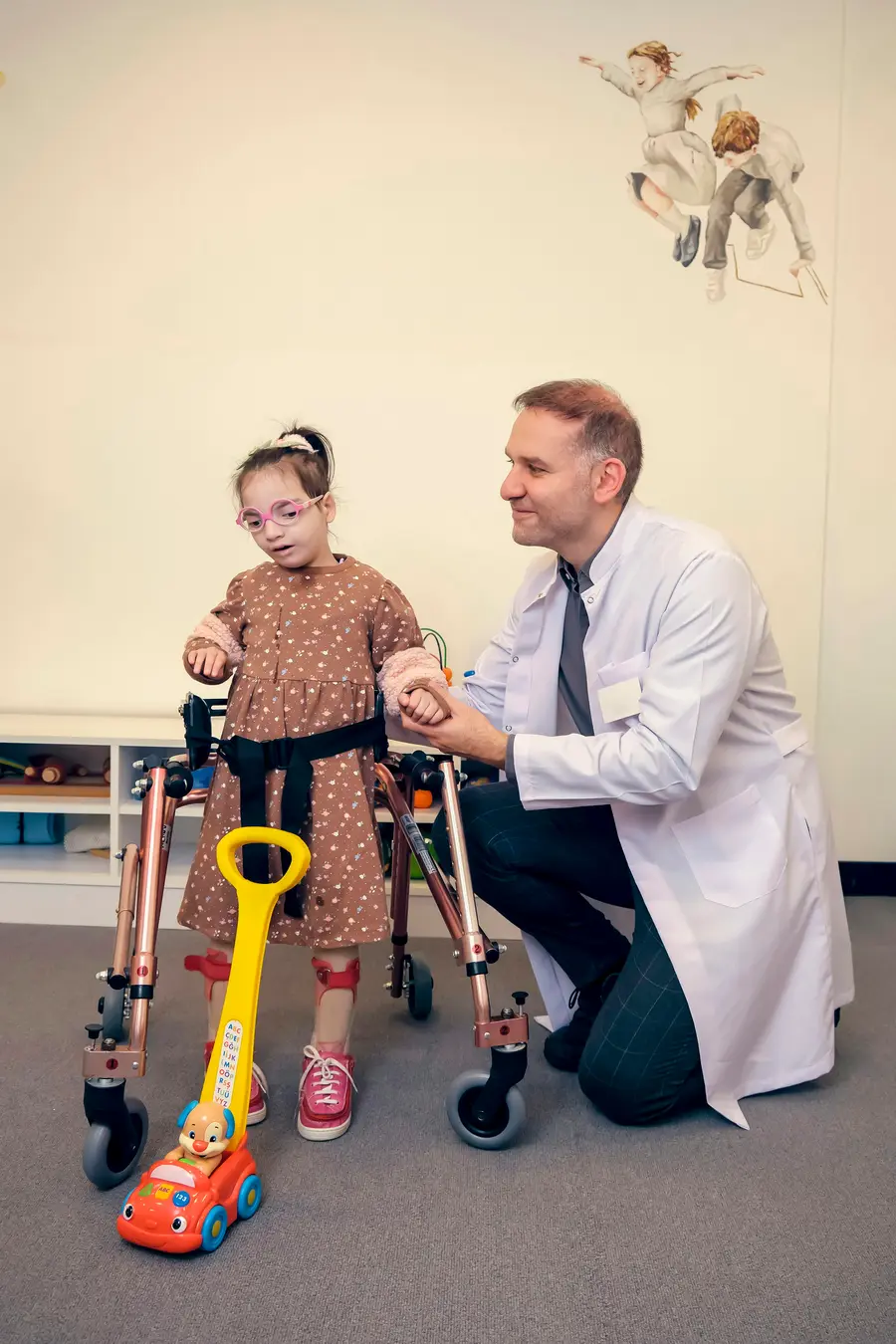 Terapeuta sorridente sentada no chão com uma criança pequena montando um quebra-cabeça colorido, sala clara