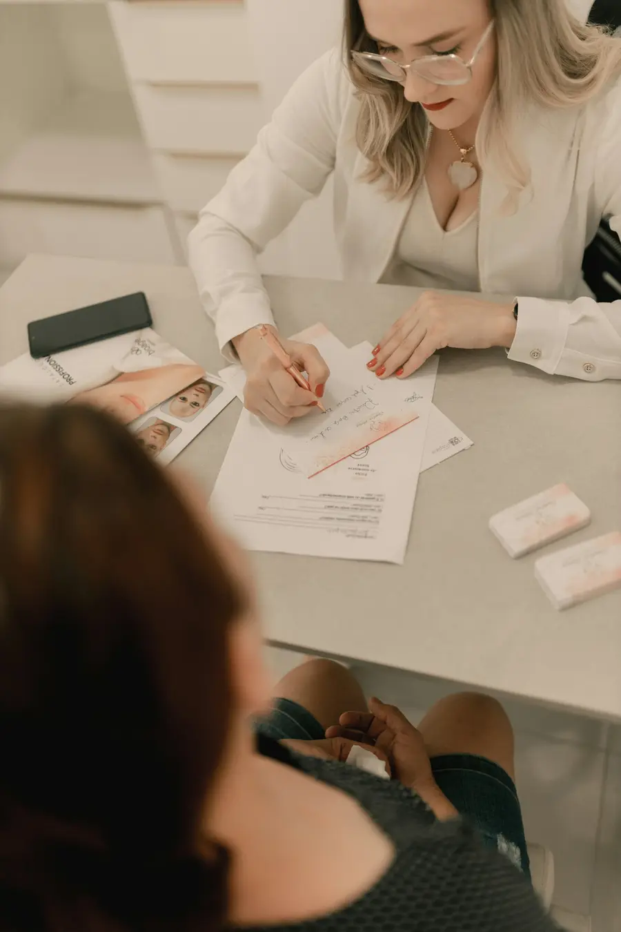 Ginecologista sorridente conversando com uma paciente adulta em consultório claro e detalhes em azul