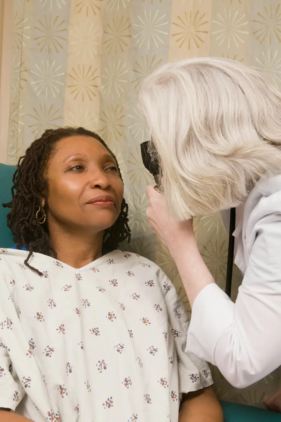 Médica sorridente conversando com uma paciente idosa num consultório claro, com detalhes em azul