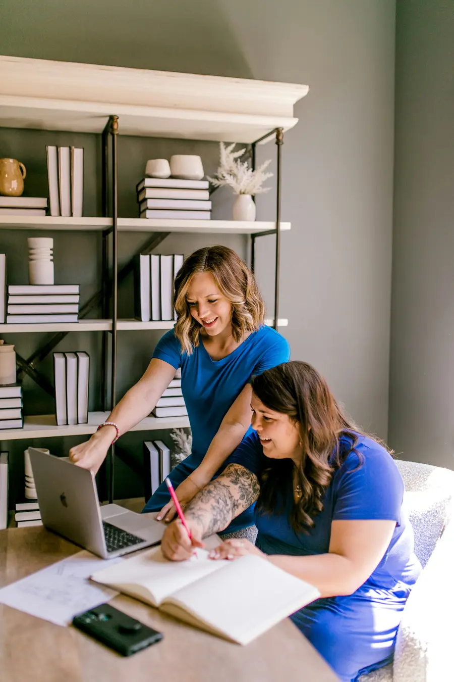 Dois sócios de uma pequena empresa conversando diante de um notebook num escritório claro e detalhes em azul