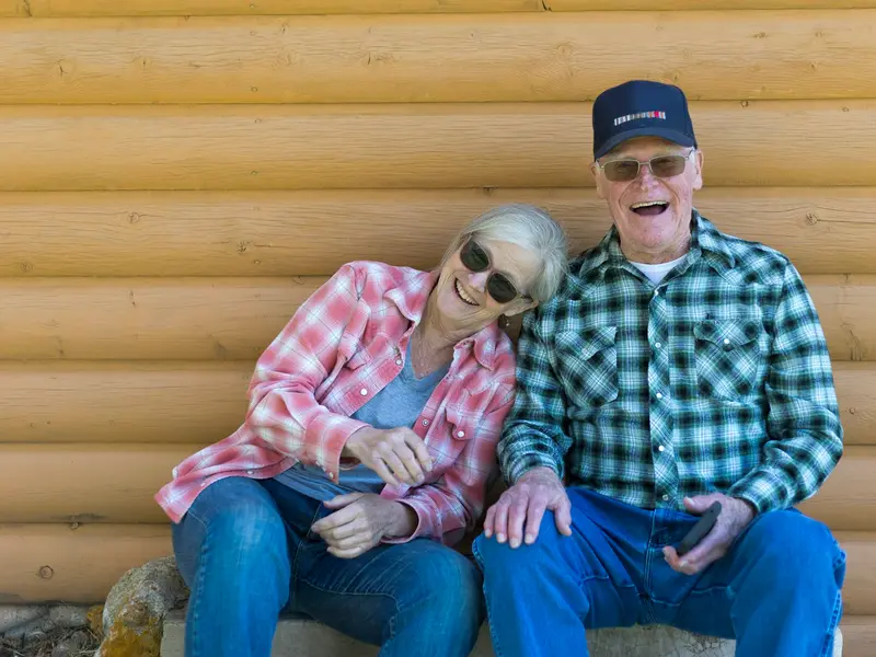 Casal de idosos sorrindo ao ar livre num dia de céu azul