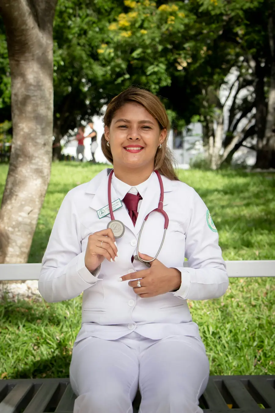 Médica sorrindo com estetoscópio no pescoço, ao ar livre