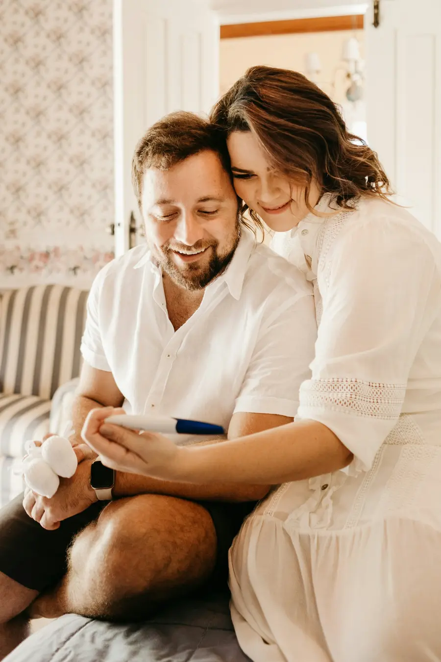 Casal sorridente olhando o celular juntos em casa clara