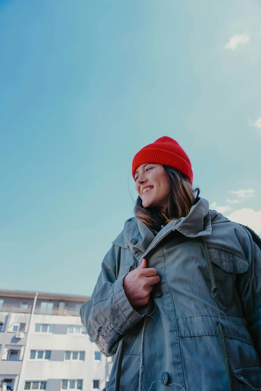 Mulher de gorro vermelho sorrindo sob céu azul