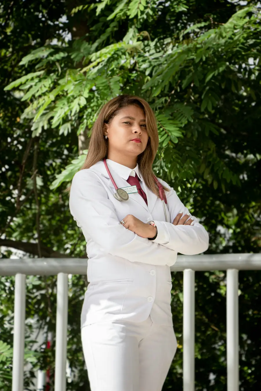 Médica de jaleco em pé numa varanda com plantas