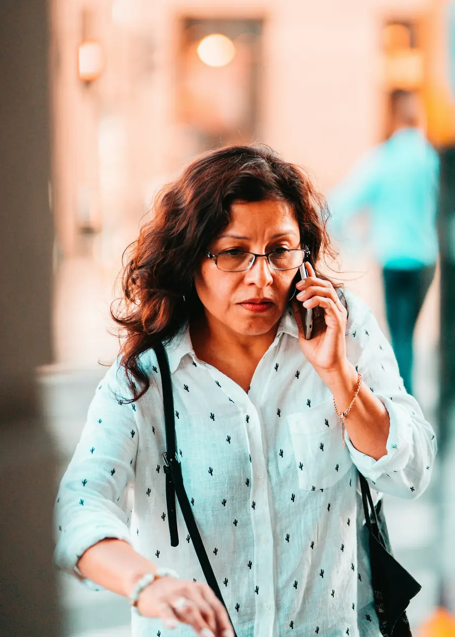 Mulher madura sorridente usando o celular em casa clara e tons de azul