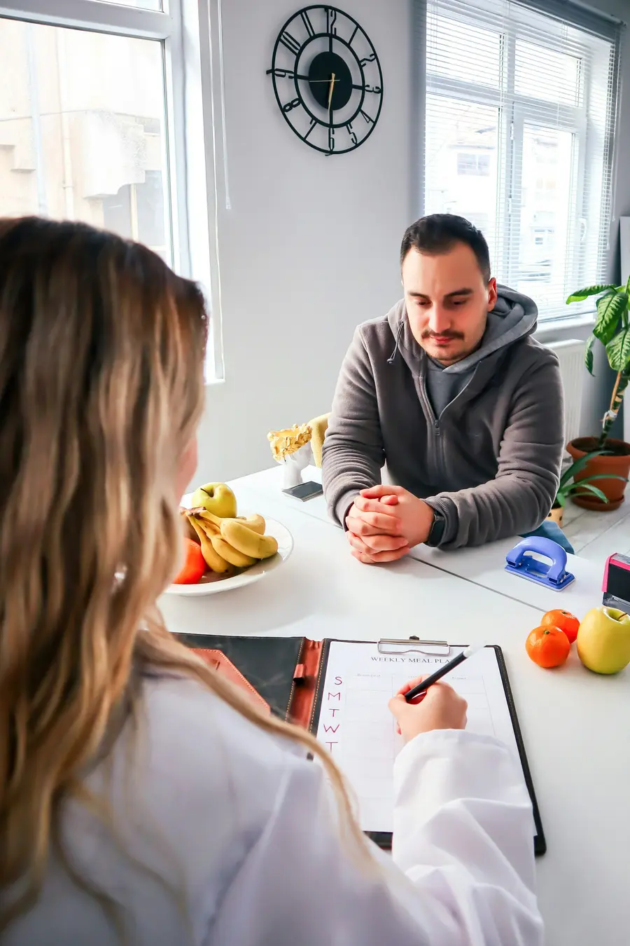 Paciente conversando com a nutricionista à mesa do consultório