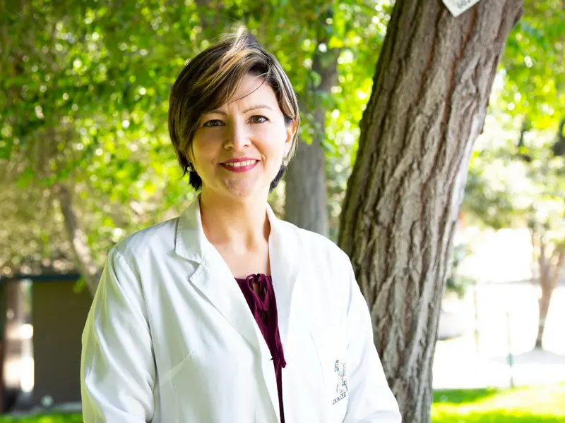 Médica de jaleco sorrindo ao ar livre