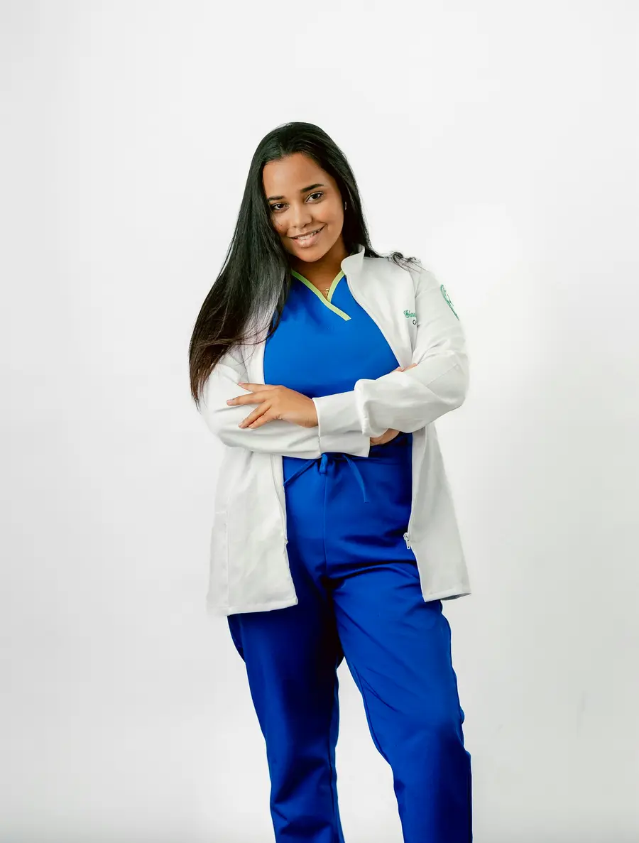 Enfermeira de uniforme azul e jaleco branco sorrindo