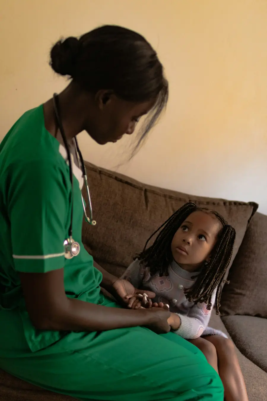 Médica sorridente atendendo criança com a mãe em consultório pediátrico claro e colorido