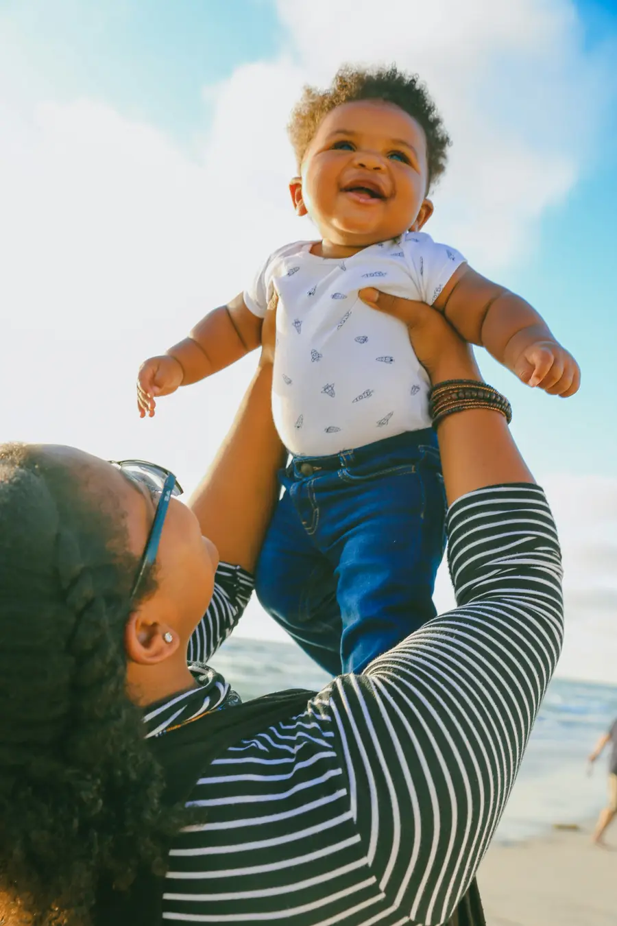 Bebê sorridente erguido contra o céu azul