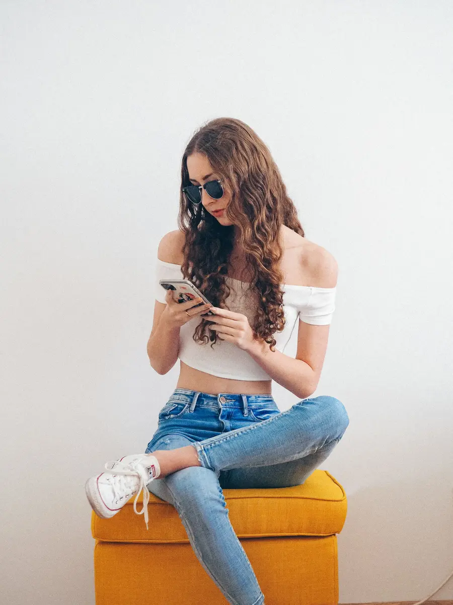 Mulher usando o celular sentada numa cadeira