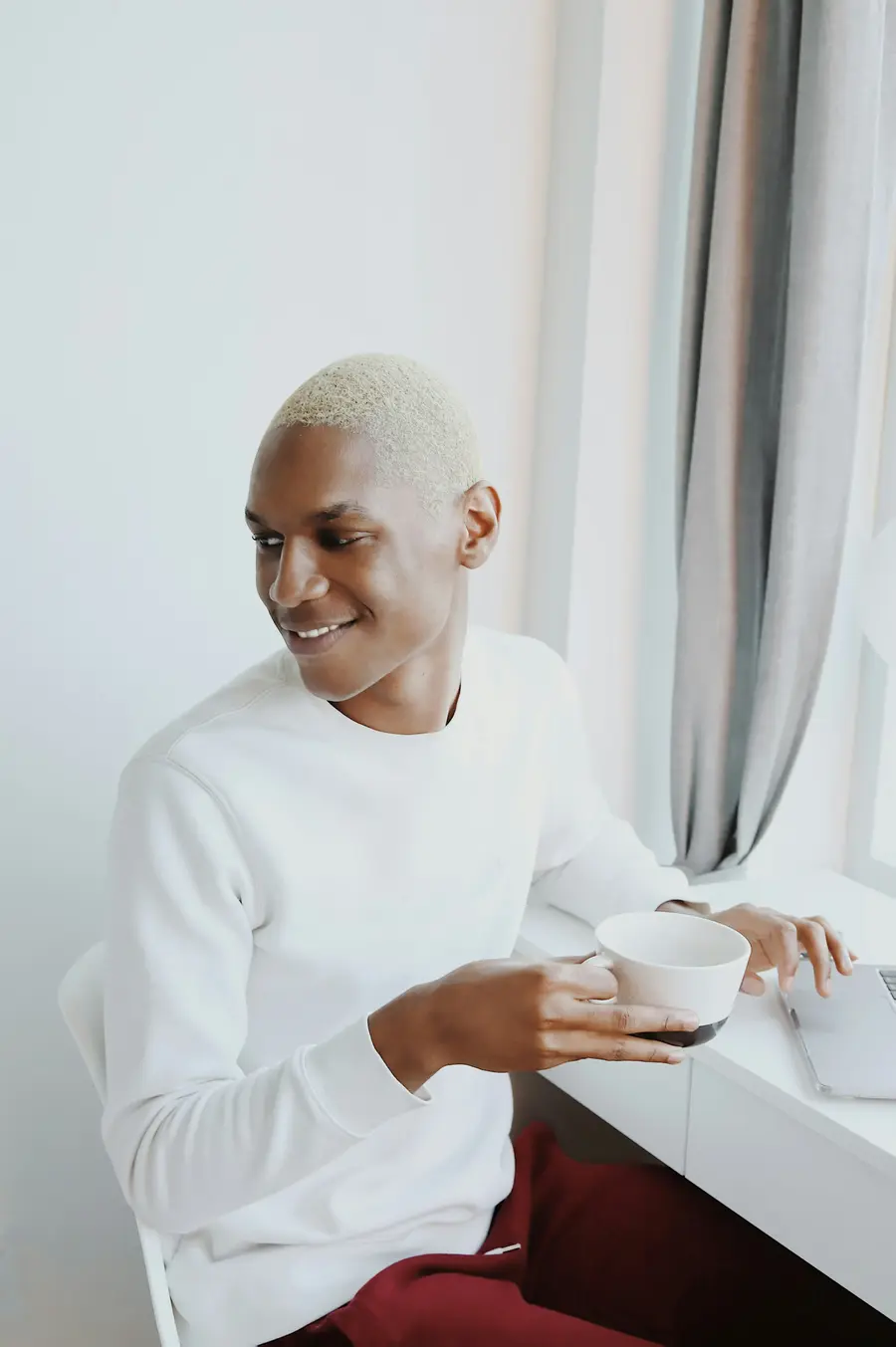 Homem rindo com uma caneca na mão