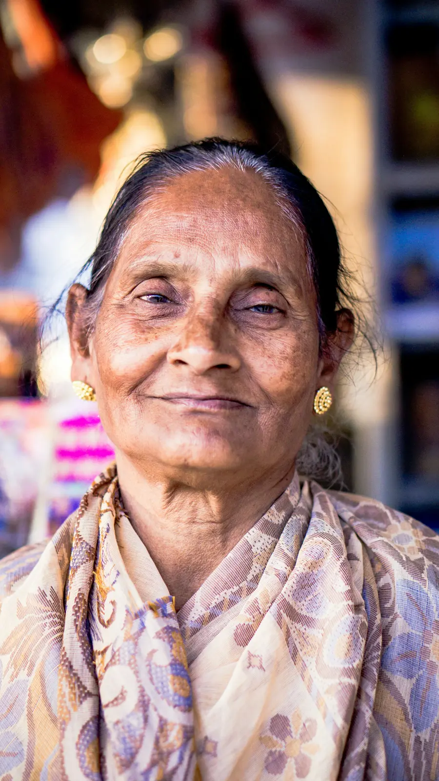 Mulher de uns 65 anos sorrindo em aula de alongamento em sala clara e colorida