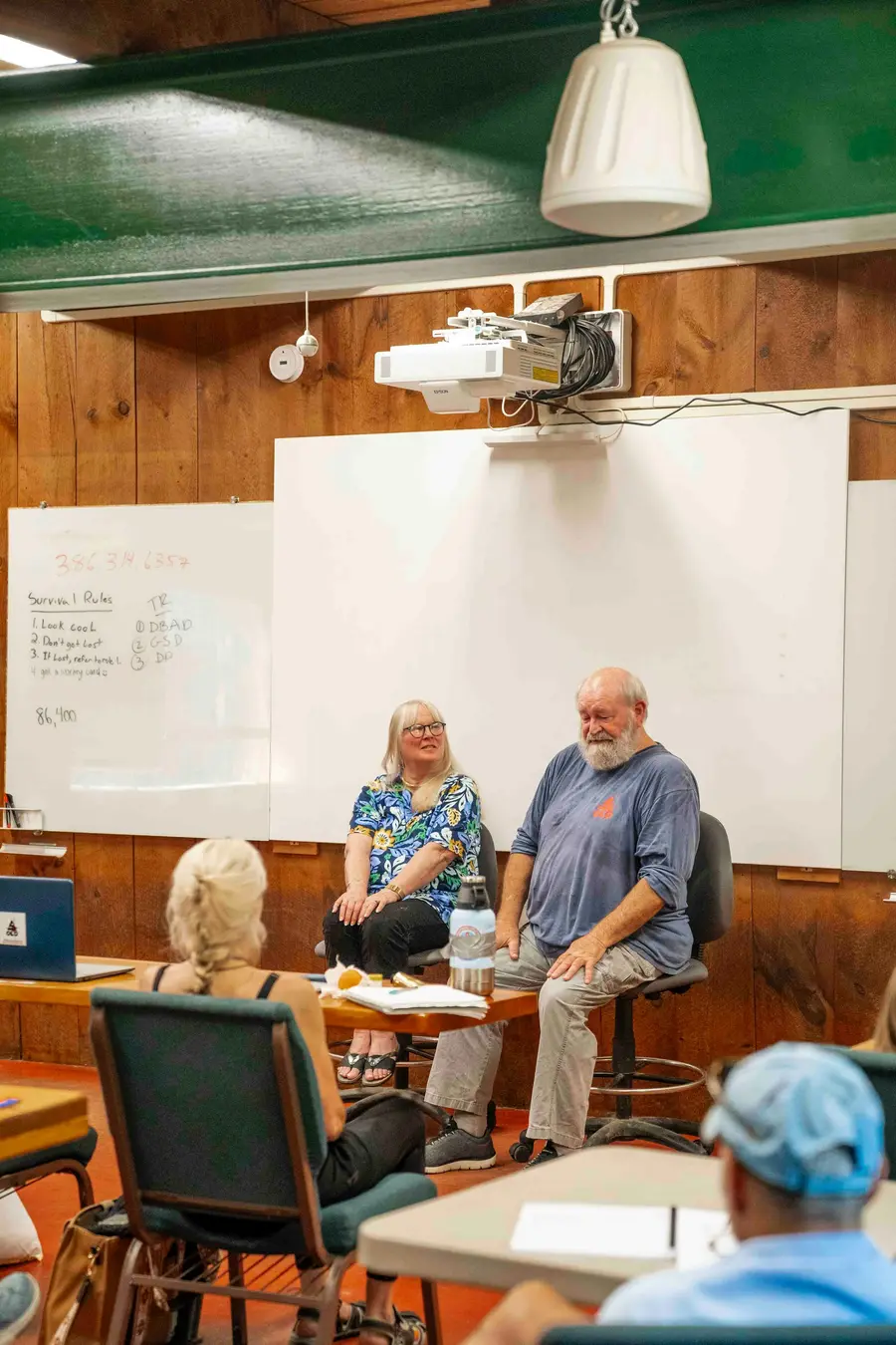 Médico de uns 50 anos sorrindo conversando com casal de uns 65 anos em clínica clara