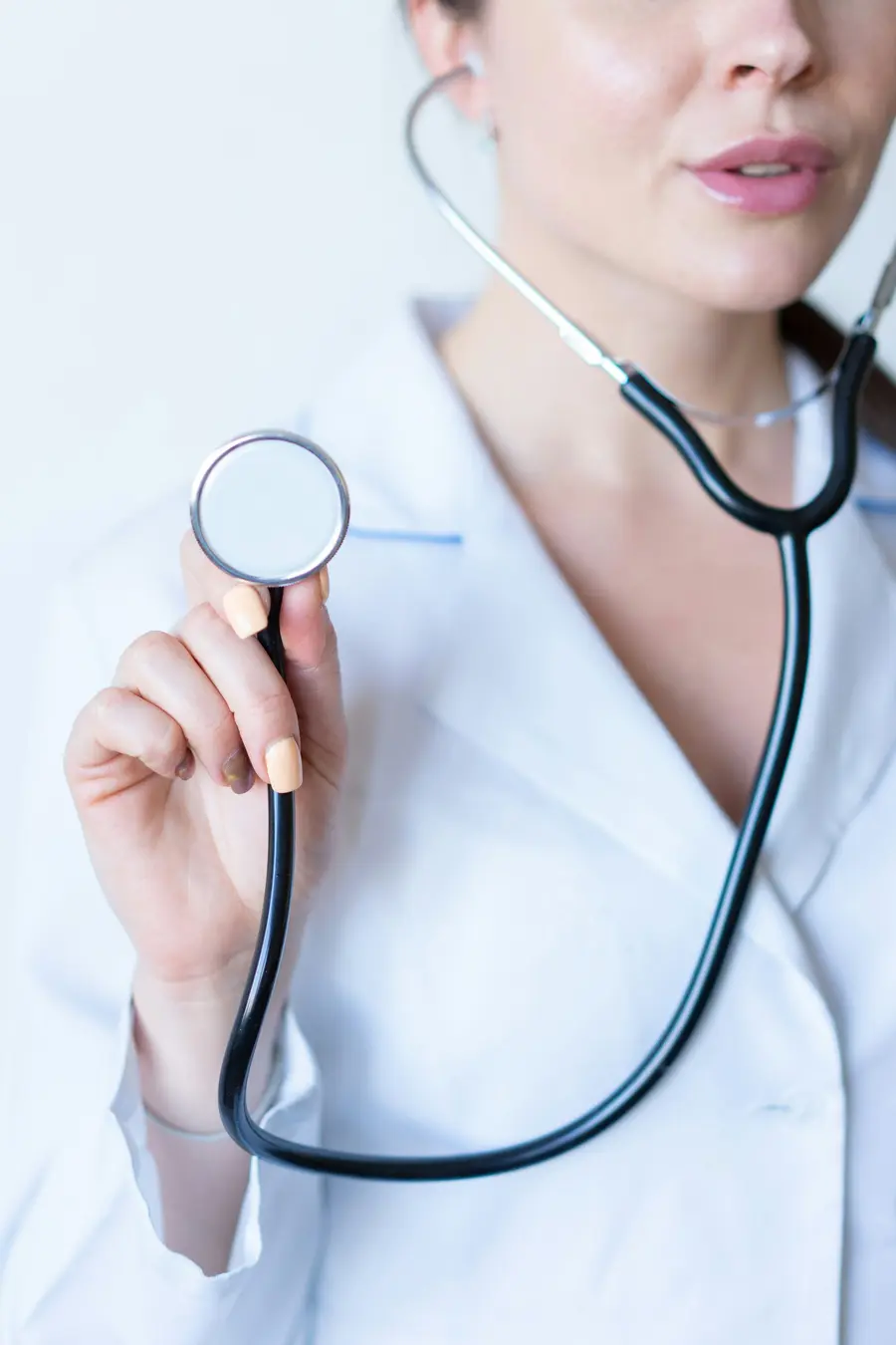 Médica sorridente de jaleco em consultório claro e detalhes em azul