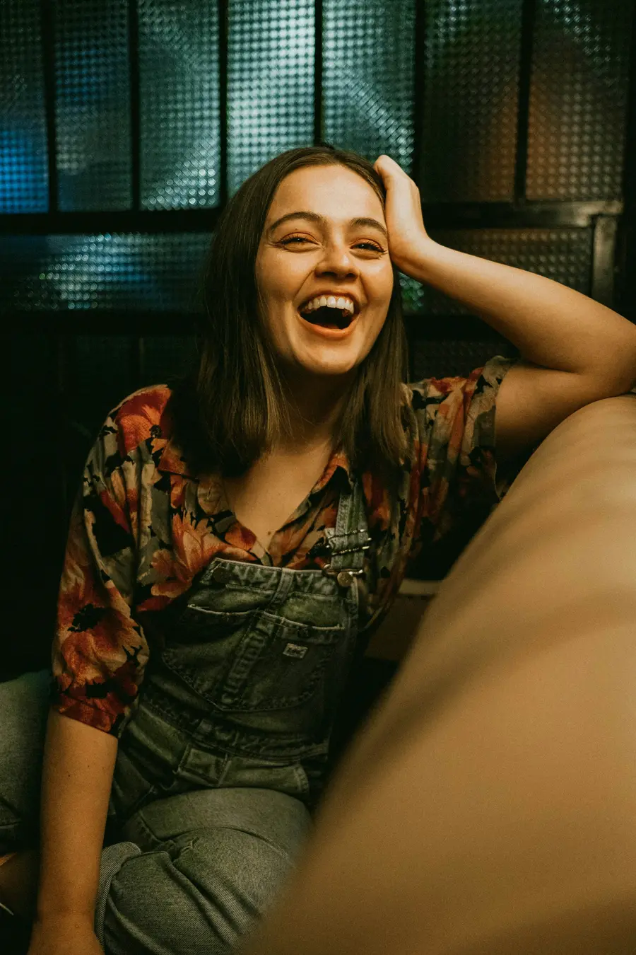 Mulher rindo sentada no sofá