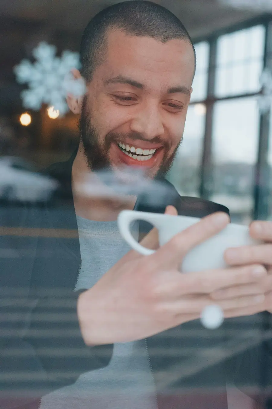 Homem sorridente conferindo valores no celular num café claro e detalhes em azul