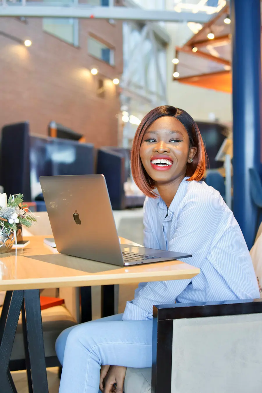 Jovem empreendedor sorridente com notebook numa oficina ou estúdio claro e detalhes em azul