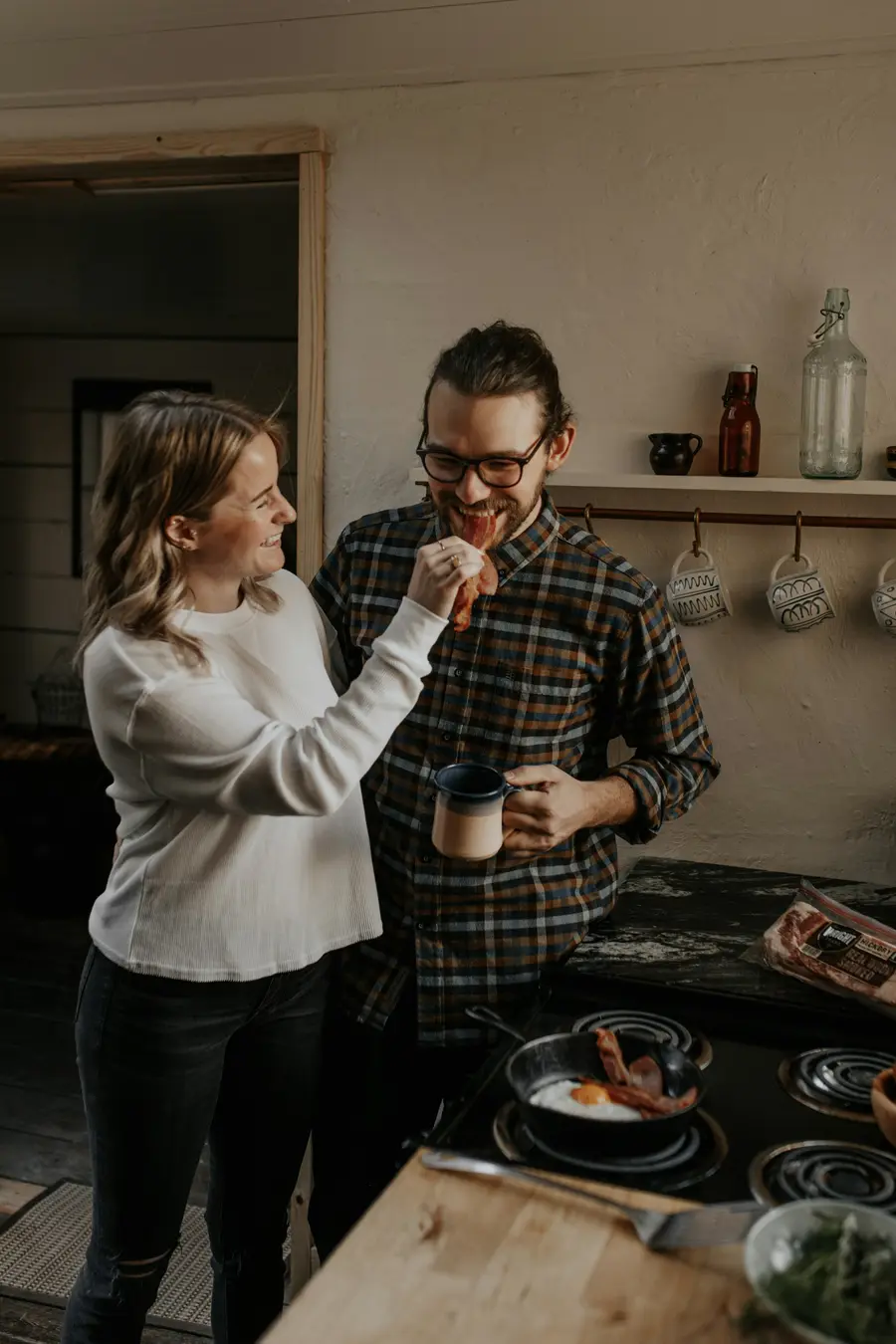 Casal de uns 50 anos sorrindo enquanto conversa na cozinha clara