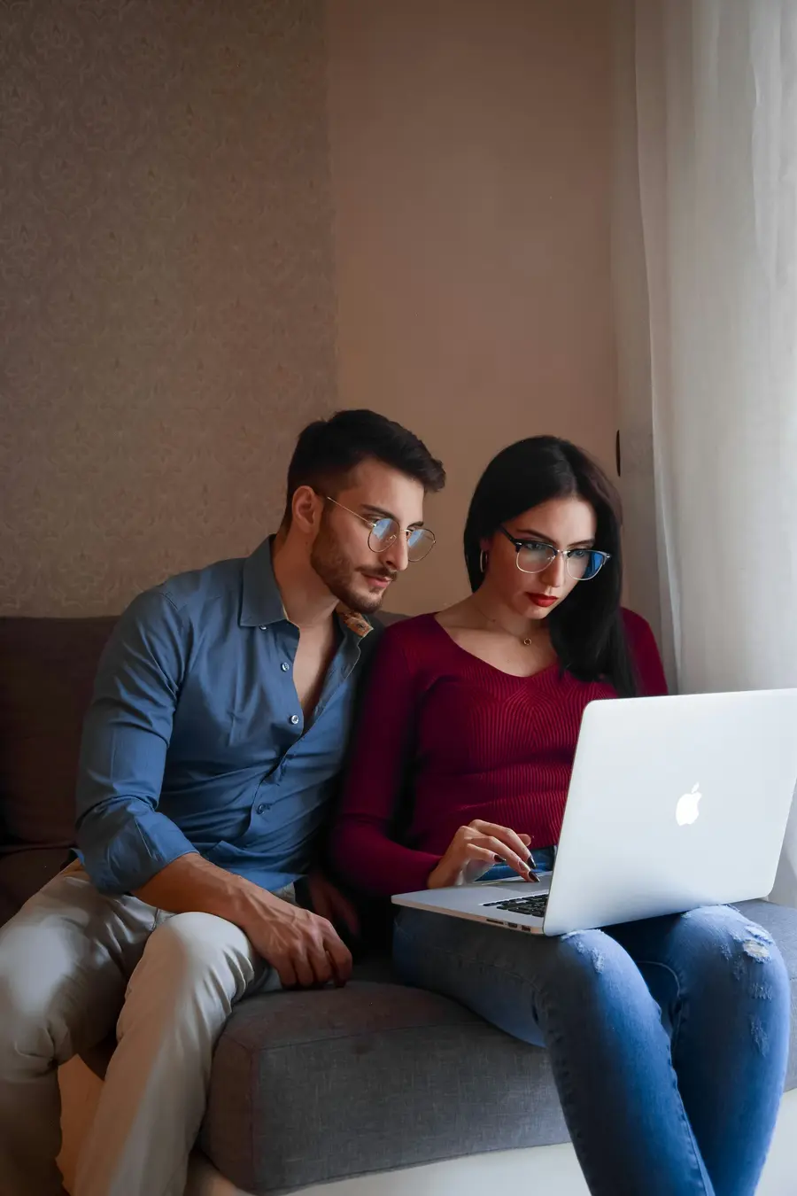 Casal olhando o notebook juntos no sofá