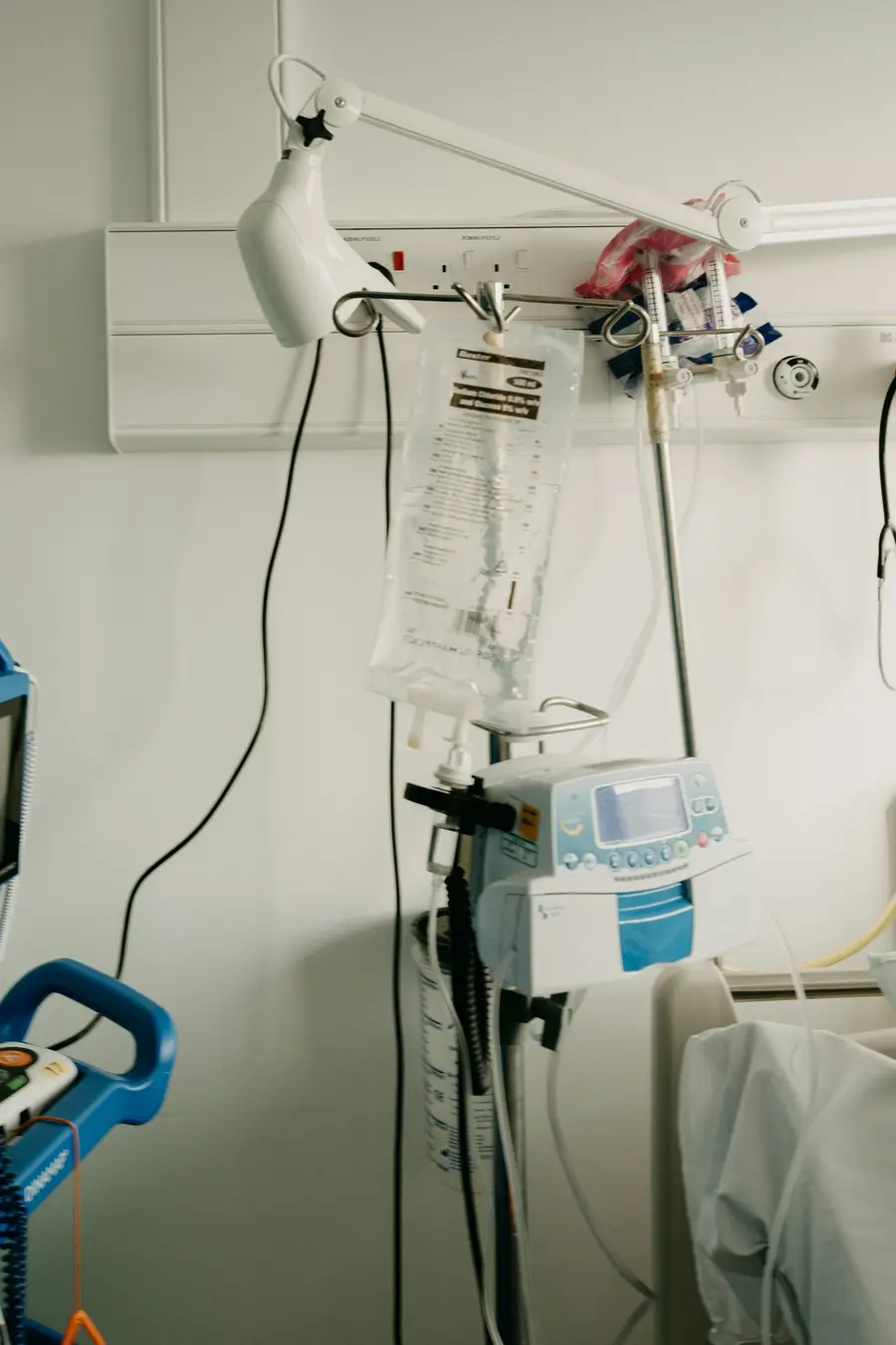 Homem de meia-idade sorridente sentado num quarto de hospital claro e moderno, recebendo alta e tons de azul