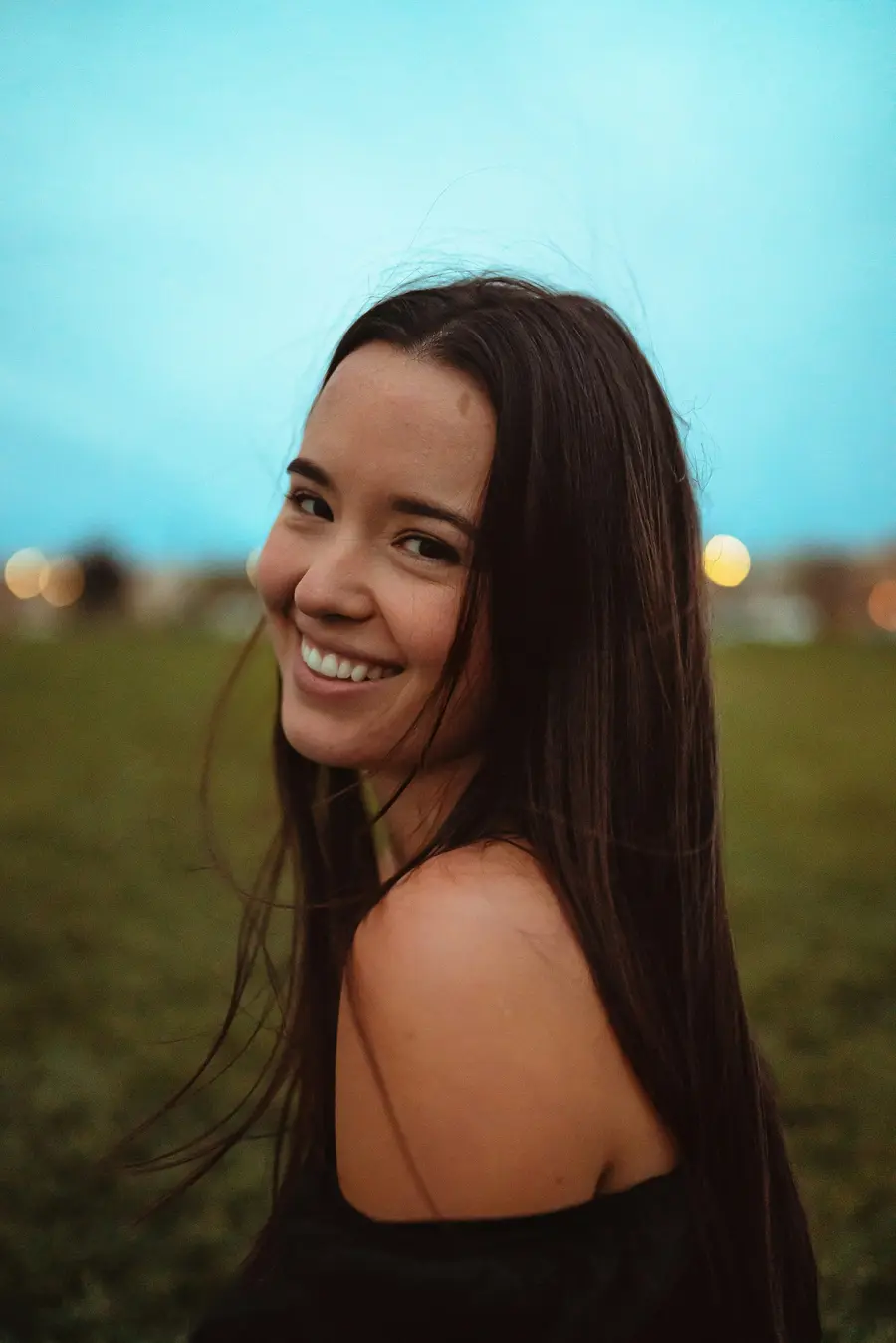 Adolescente sorrindo com aparelho fixo nos dentes, ao ar livre num dia claro