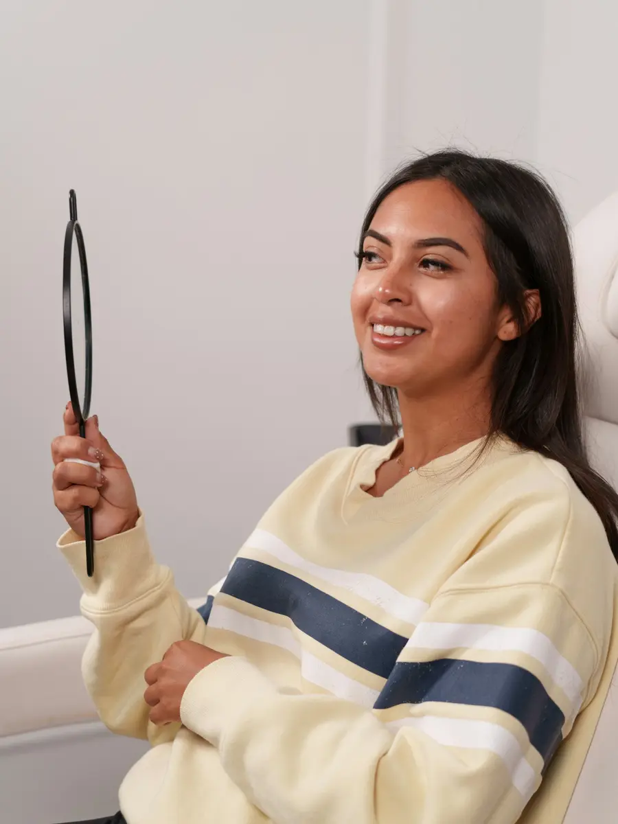 Paciente sorrindo sentada na cadeira do dentista e limpo, tons de branco e azul