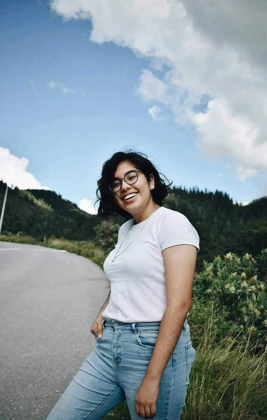 Mulher de camiseta branca sorrindo ao ar livre