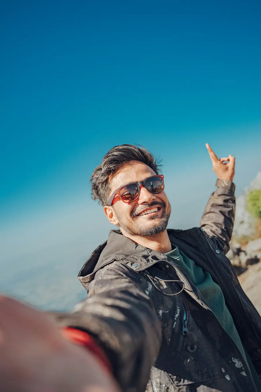 Homem de óculos escuros sorrindo sob céu azul