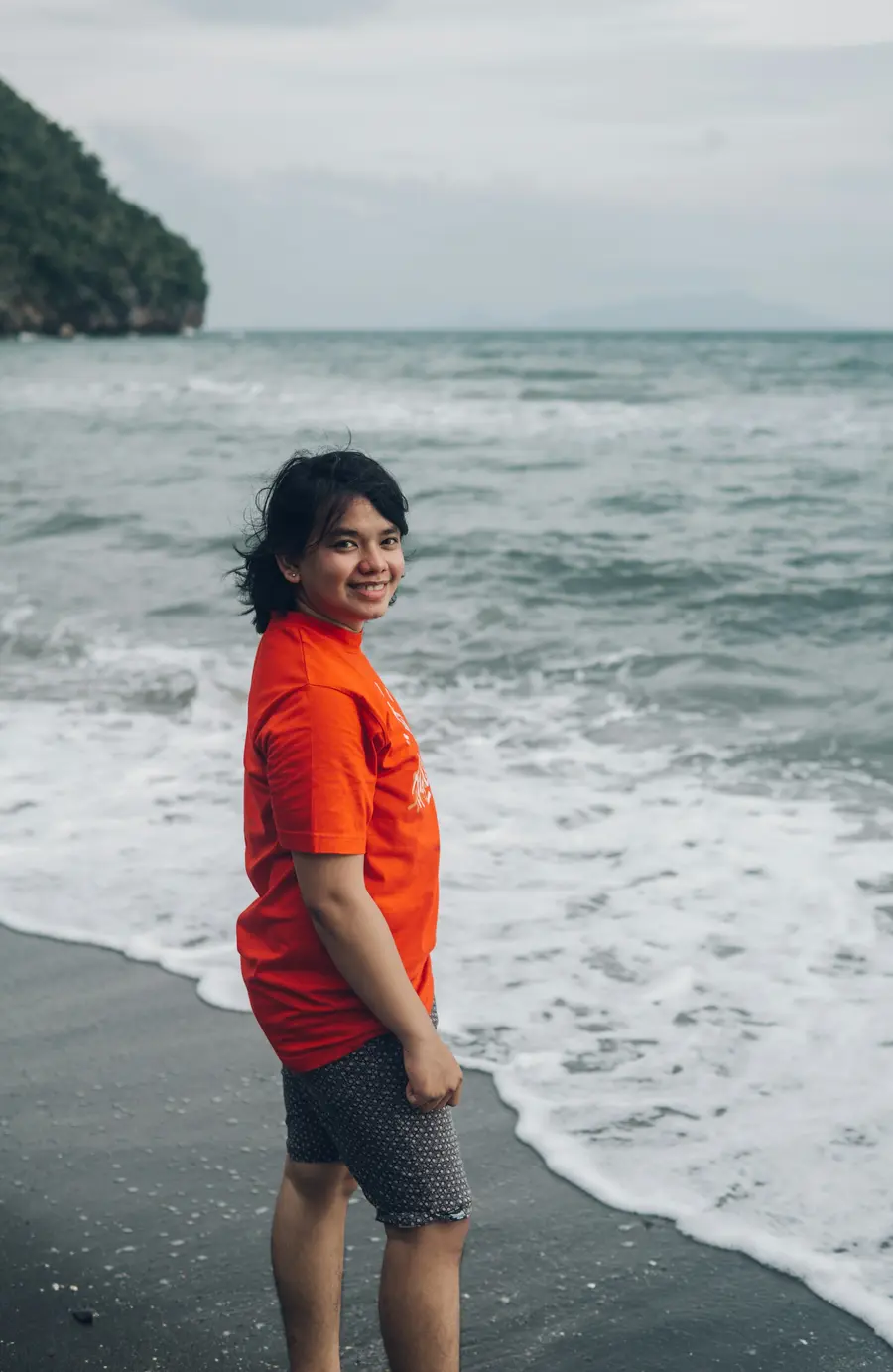 Pessoa de camiseta laranja na beira da praia