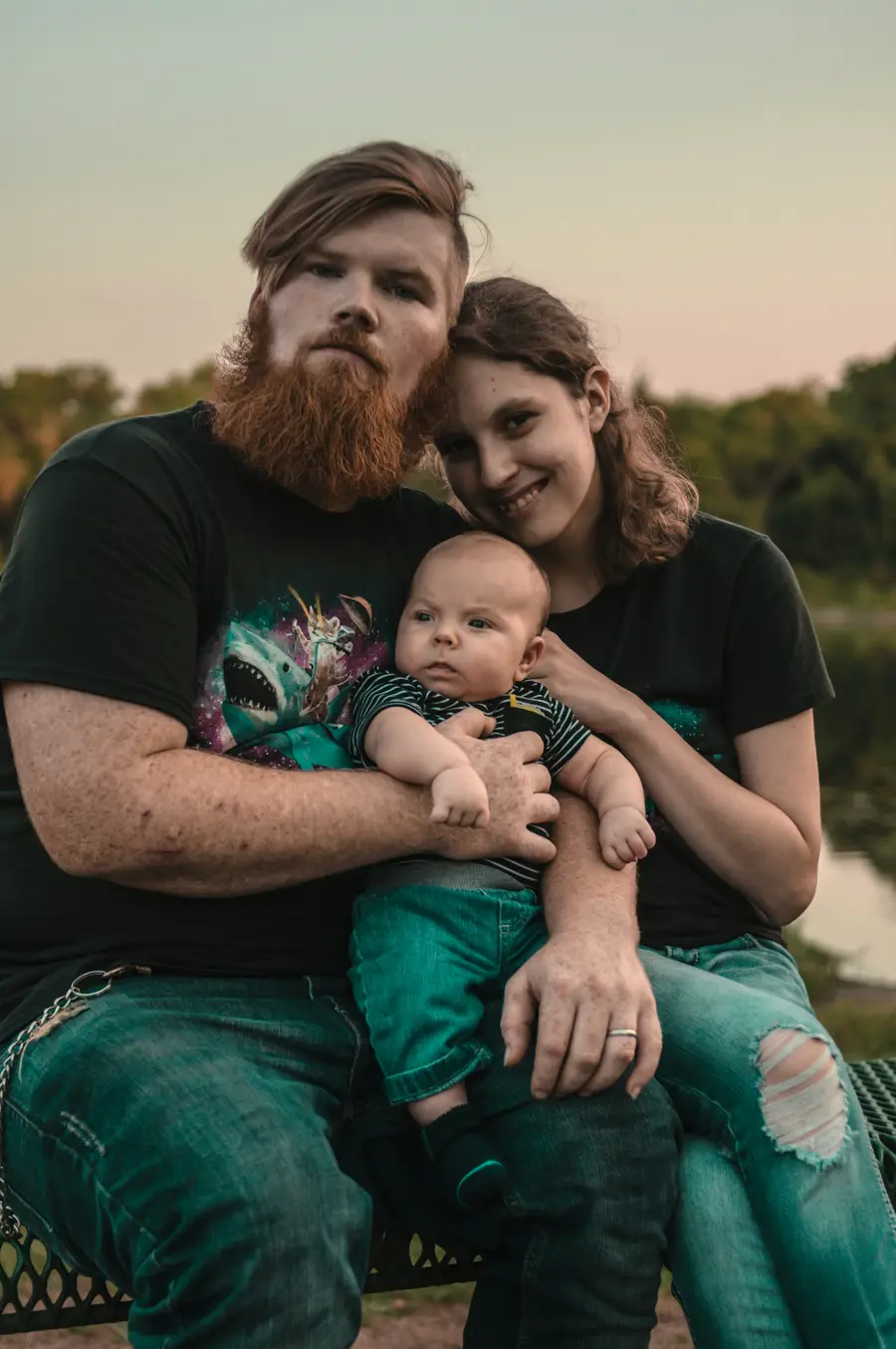 Casal jovem sorridente com um bebê no colo, em casa