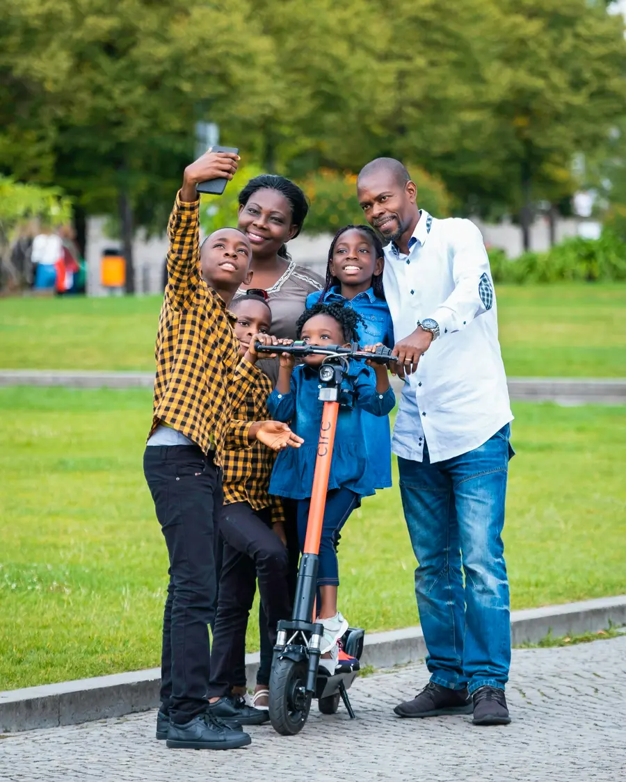 Família sorrindo num parque de Curitiba, como o Parque Barigui, com árvores e céu azul