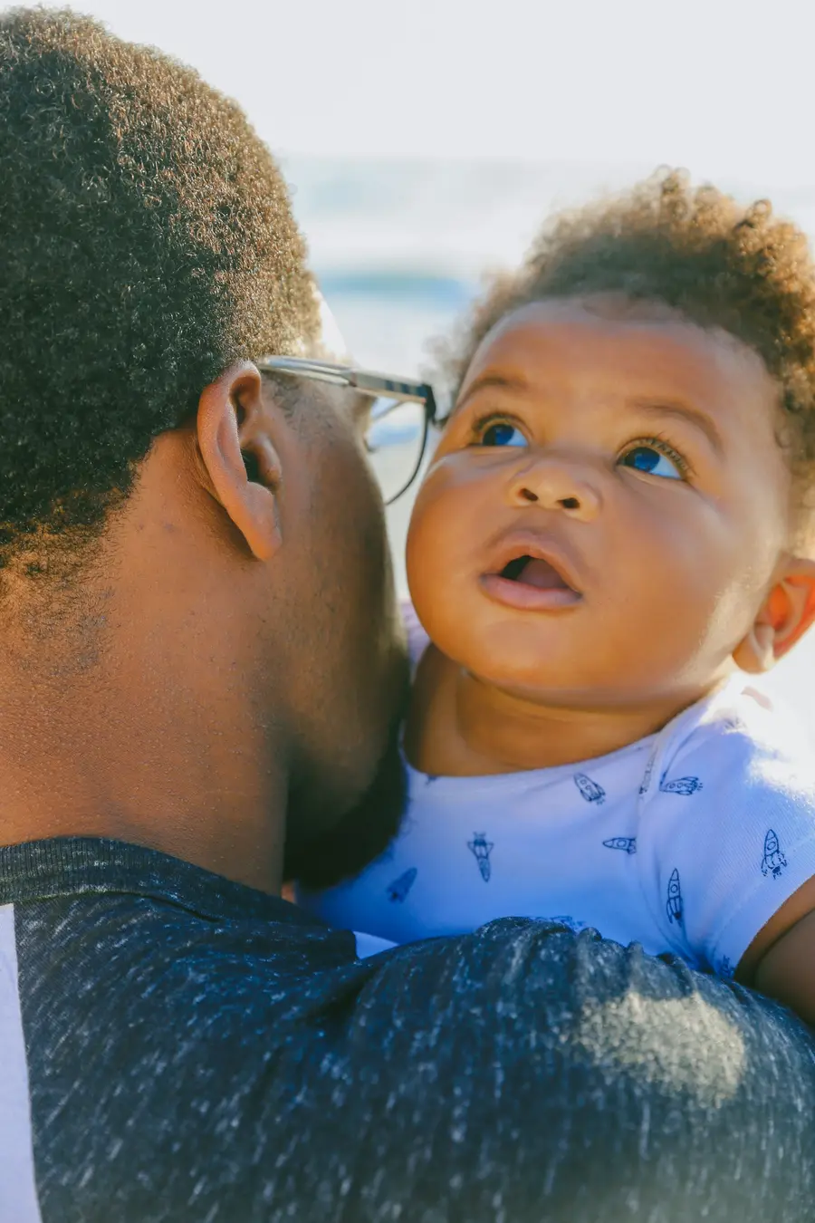 Família sorridente com criança pequena ao ar livre, à beira-mar, céu azul