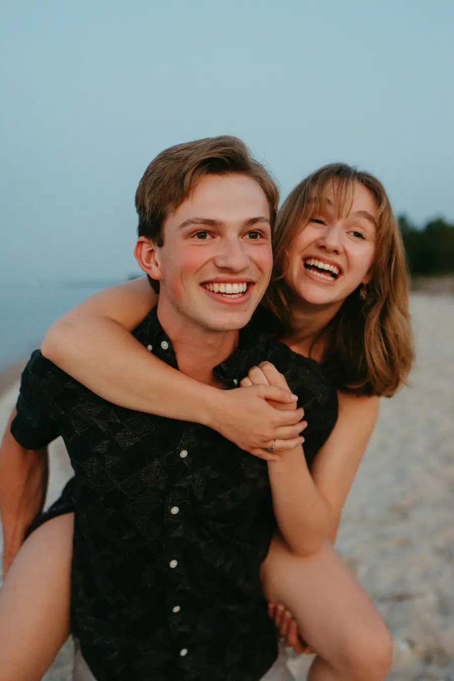 Casal sorrindo na orla do Guaíba, em Porto Alegre, céu azul