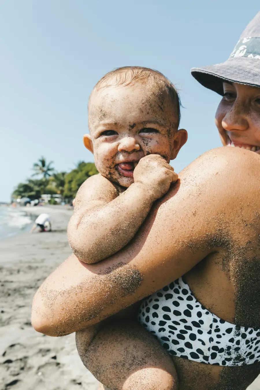 Família sorrindo na praia de Boa Viagem, em Recife, mar e céu azul