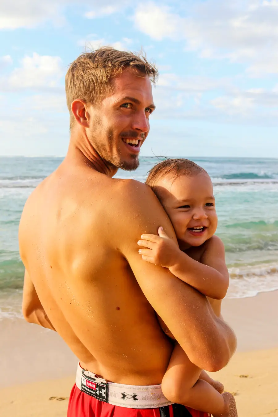 Família sorrindo na orla de Salvador, com o mar e o céu azul ao fundo