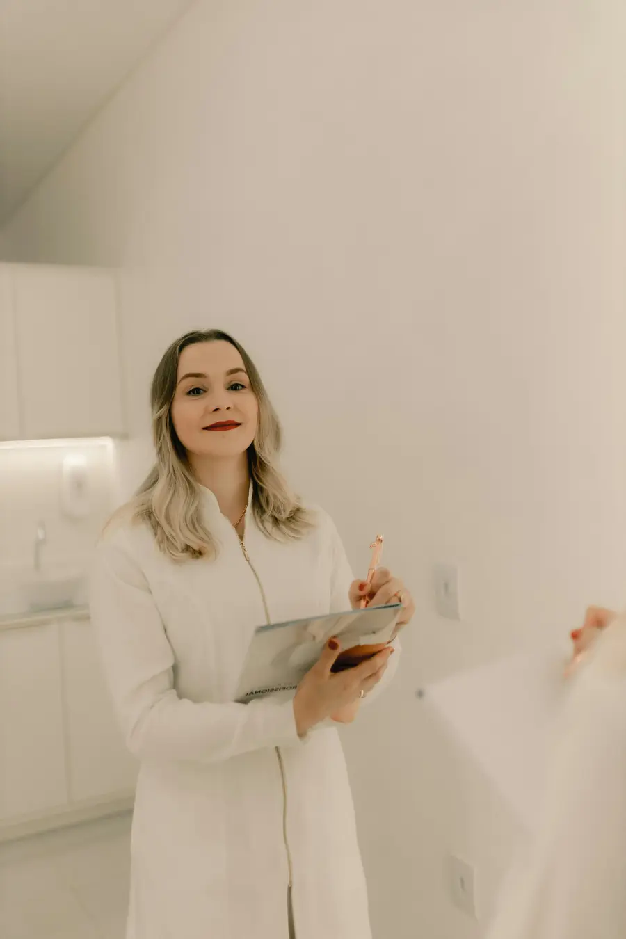 Jovem sorridente em consulta com uma médica em consultório claro, jaleco branco e detalhes em azul