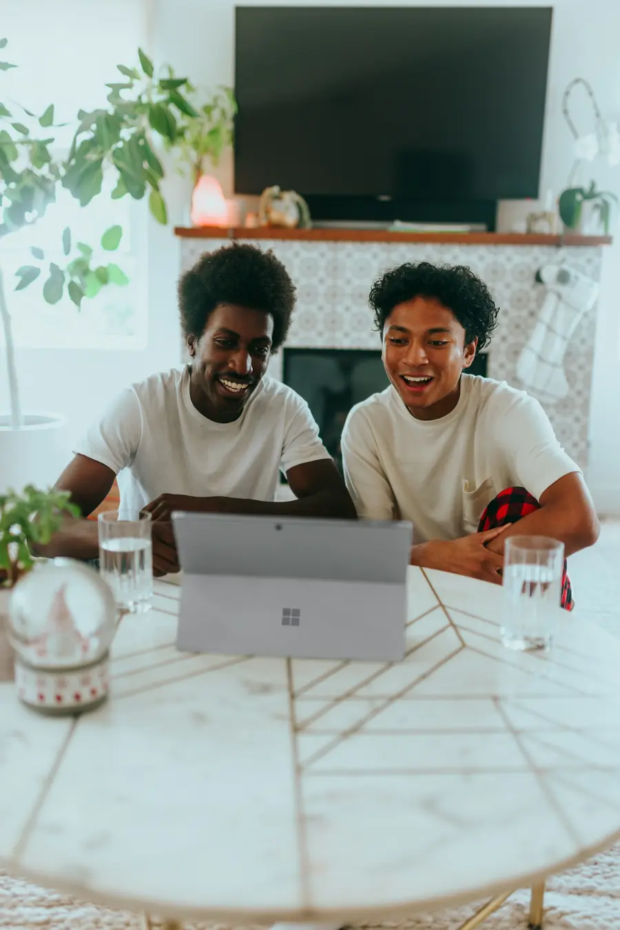 Dois amigos sorrindo diante do notebook