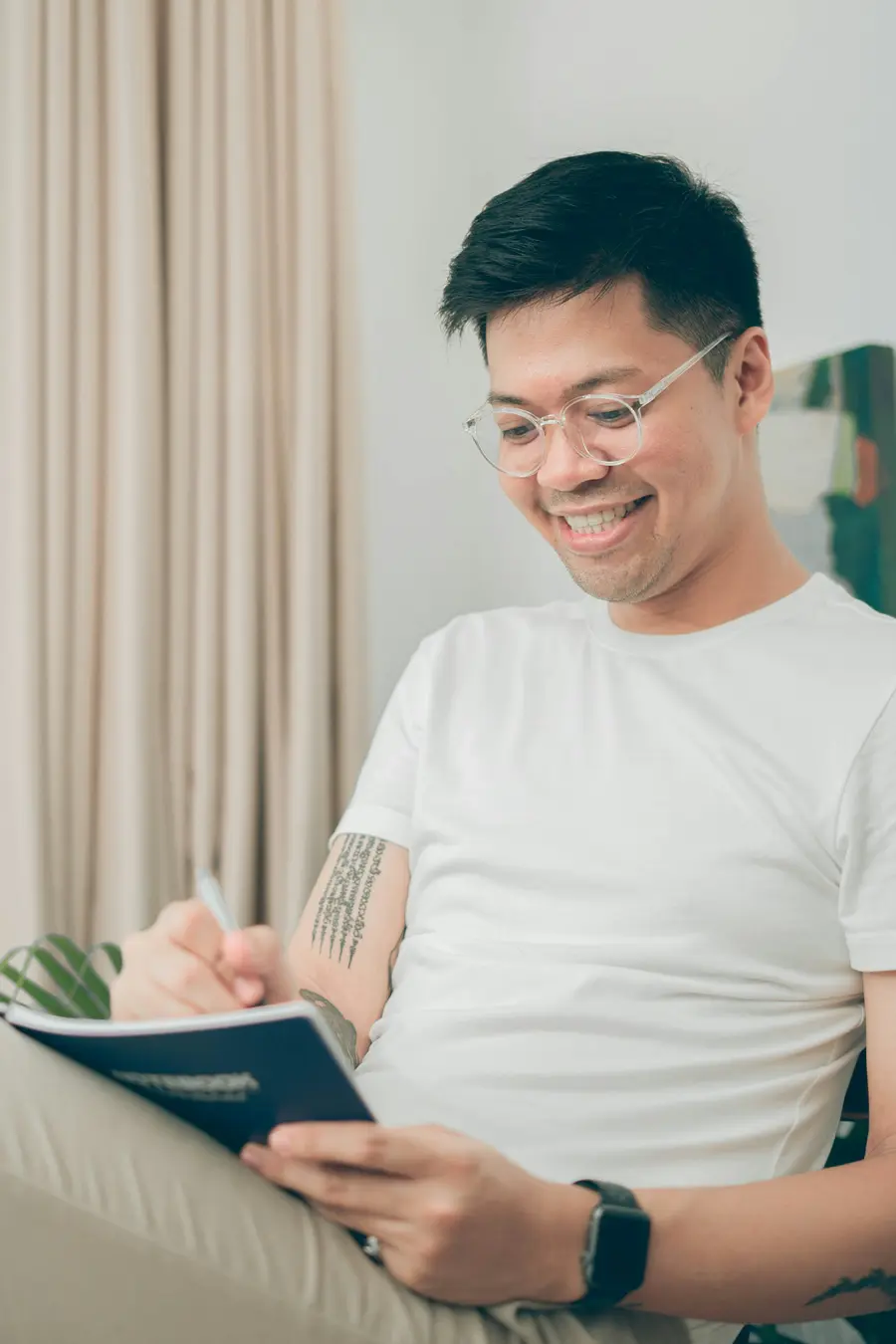 Homem sorrindo enquanto lê um caderno