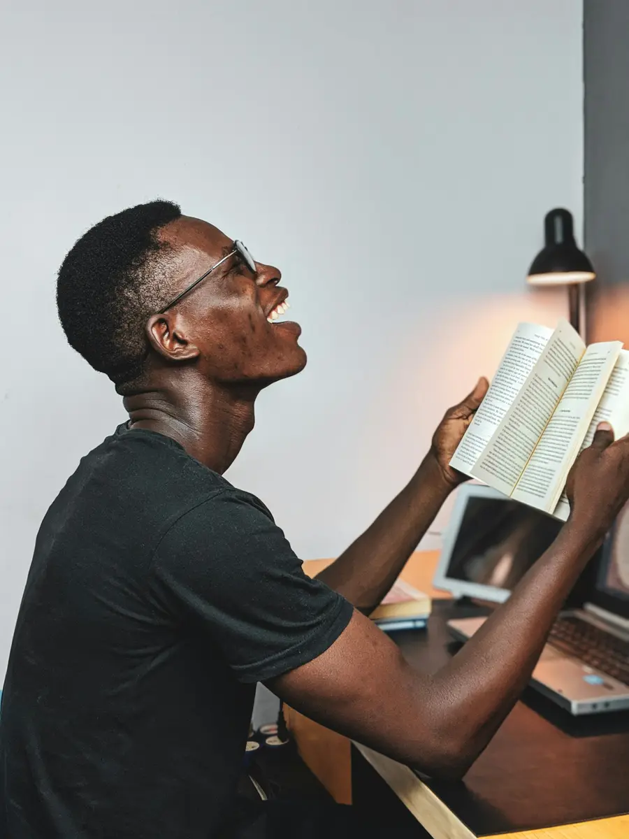 Homem sorrindo enquanto lê um livro