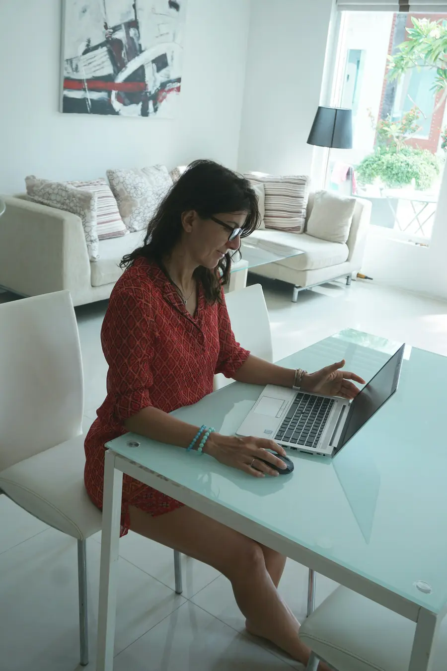 Mulher jovem sorridente usando notebook numa mesa clara em casa