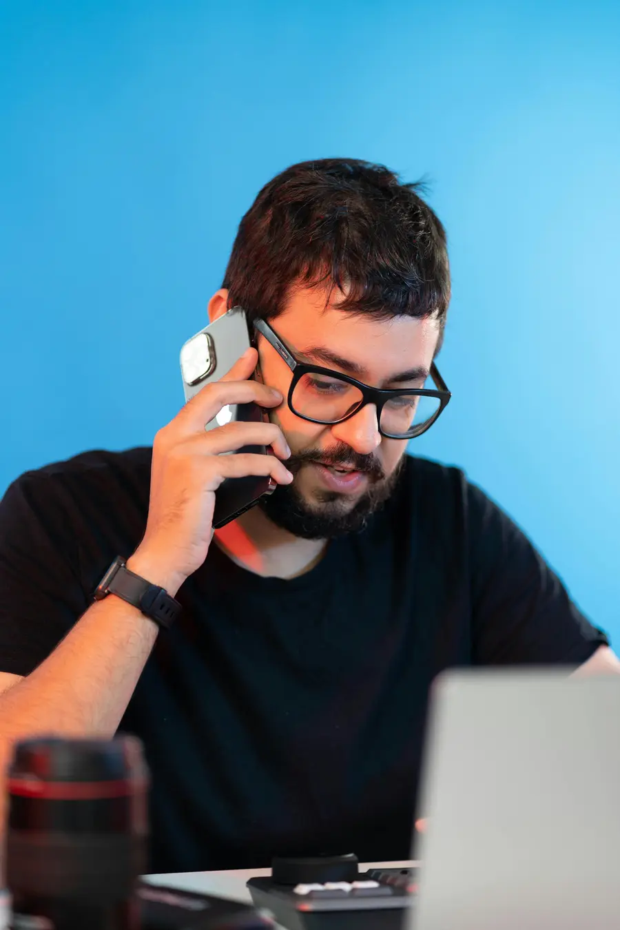 Jovem empreendedora sorridente no próprio estúdio claro, segurando o celular